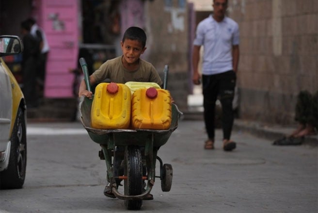 Một cậu bé người Yemen đang đẩy xe chở những chiếc thùng đựng đầy nước ở San’a vào tháng 6/2013 - Tin: WSJ/Ảnh: EPA.