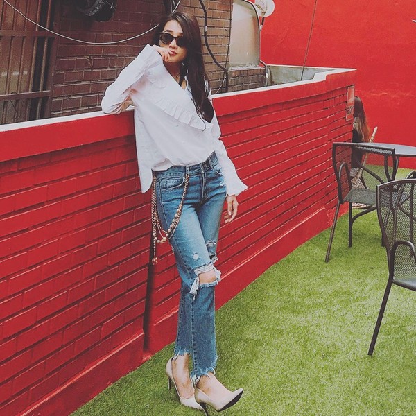 Áo sơ mi trắng bèo nhún cách điệu được Nhã Phương kết hợp với jeans rách trẻ trung.  