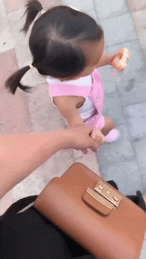 Cô bé Chloe cột tóc 2 bên, vừa đi vừa ăn rất dễ thương.    