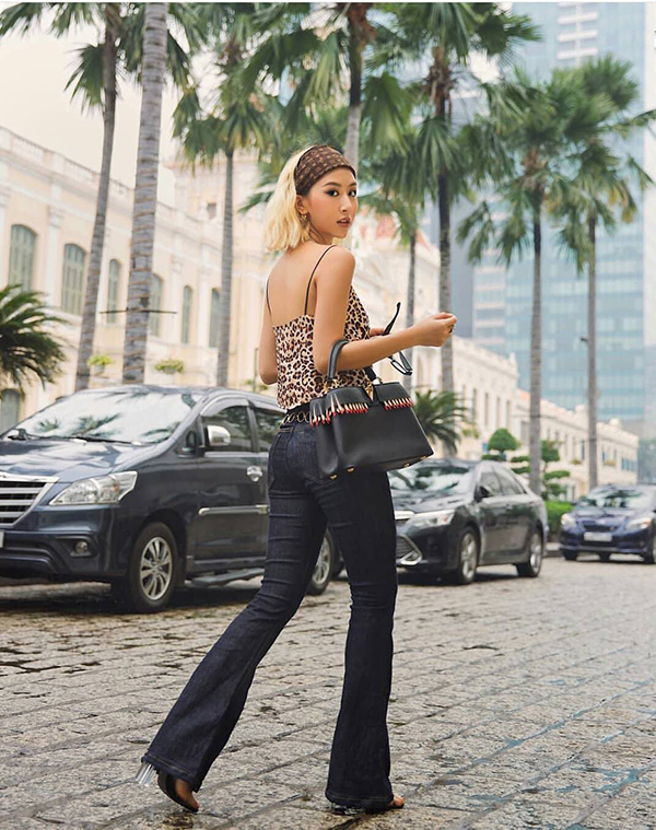 Quỳnh Anh Shyn dạo phố với set đồ mang phong cách hippie gồm quần jeans ống loe, khăn turban, áo hai dây hoạ tiết đốm da beo và sandal nhựa trong. 