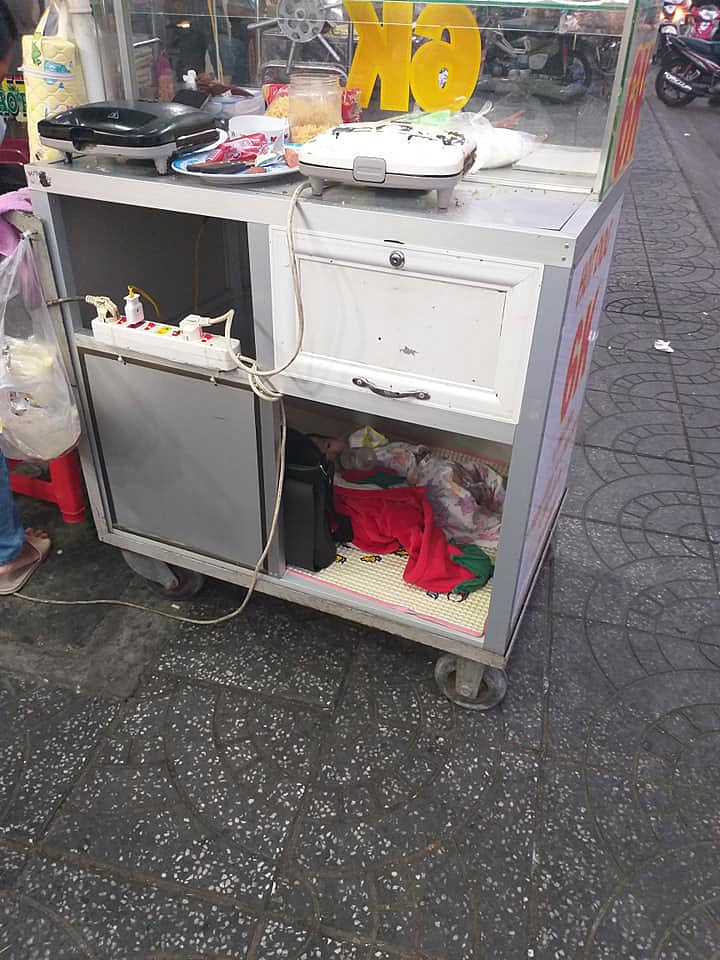 Em bé nằm trong xe hàng theo mẹ mưu sinh khắp nơi.