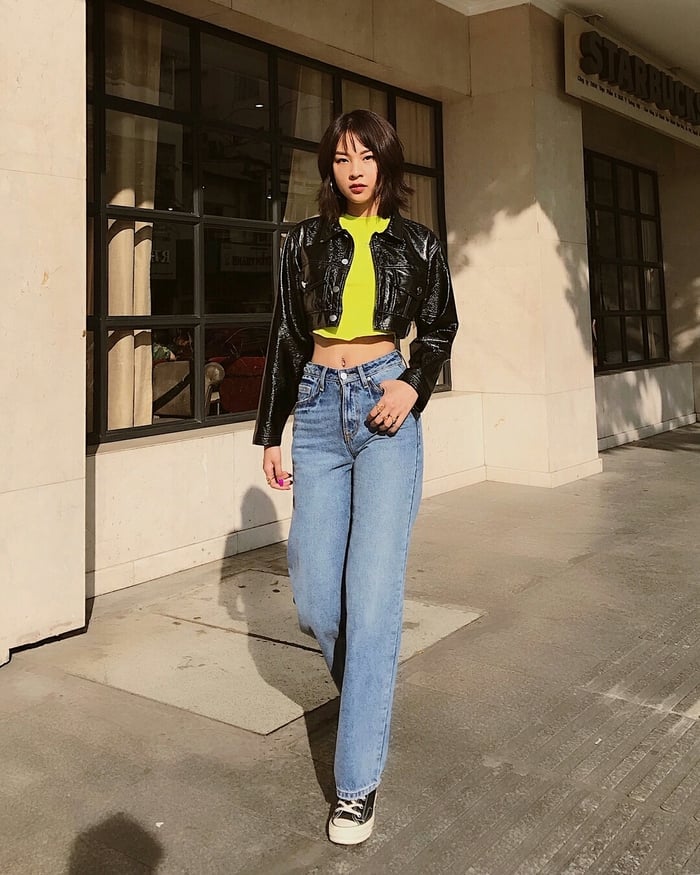 Phí Phương Anh gợi ý cách phối quần jeans kiểu cổ điển với croptop vàng chanh và áo khoác da đen bóng lộn. Giày thể thao classic là phụ kiện đi kèm chuẩn.    