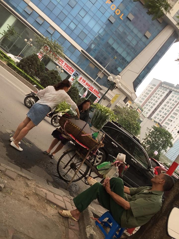 Hai cô gái vô tư đứng trước xe hoa của bác bán hoa rồi chụp chụp ảnh.