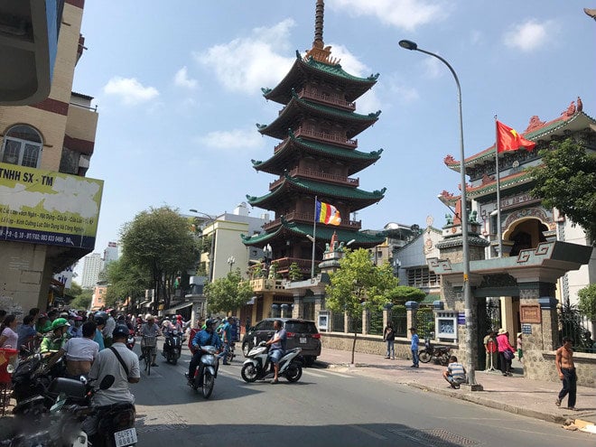 Hai bên đường trước cổng chùa, người dân đứng đông đúc.