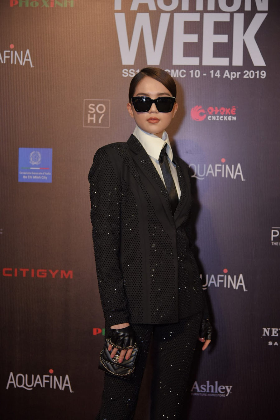 Khác với hình ảnh quyến rũ thường ngày, Ngọc Trinh tái hiện hình ảnh huyền thoại Karl Lagerfeld trên thảm đỏ Aquafina Tuần lễ Thời trang Quốc tế Việt Nam Xuân – Hè 2019. Cô diện nguyên cây âu phục, cravat, găng tay thuộc da và phụ kiện túi xách mini.    