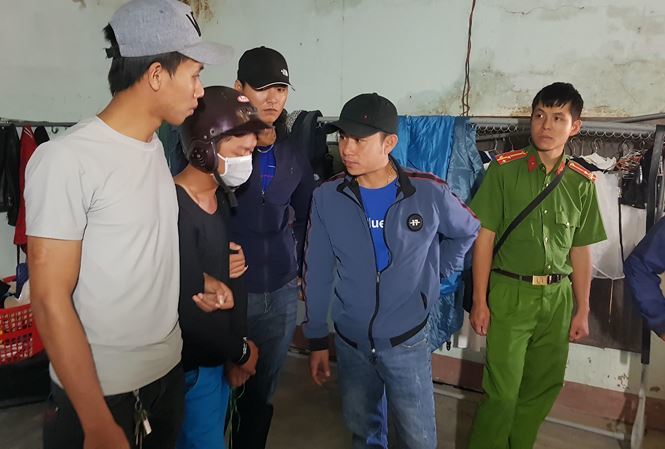 Vũ (đội mũ bảo hiểm, đeo khẩu trang) bị công an đưa đến hiện trường.