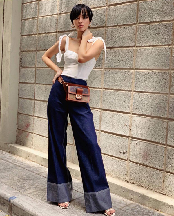 Khánh Linh The Face thể hiện sự cá tính và gợi cảm bằng việc chọn quần denim để mặc cùng áo hai dây biến tấu độc đáo. Phụ kiện túi đeo hông, sandal hợp mốt càng giúp hình ảnh của cô thu hút hơn.     