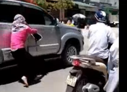 Người phụ nữ đu bám trên ô tô khi phát hiện chồng đi cùng nhân tình.