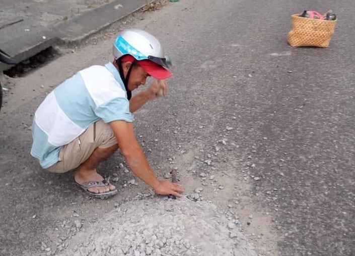 Người đàn ông miệt mài đục mảng bê tông giữa đường.