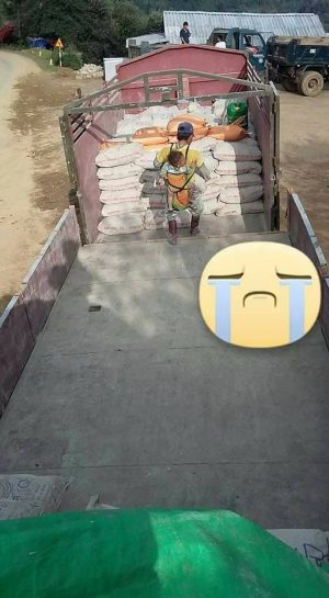 Người đàn ông địu con nhỏ đi bốc vác.