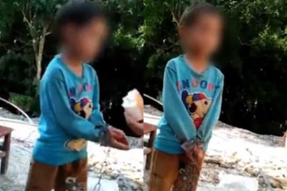 Bé trai bị xích giữa trời nắng.