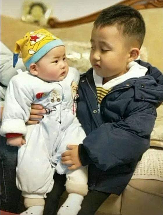 Vẻ mặt ngán ngẩm của cậu anh khi phải bế em.