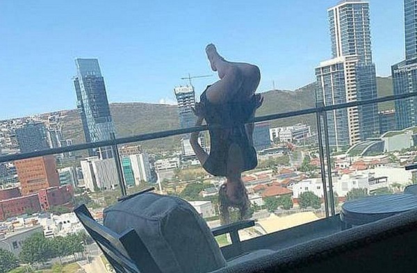 Hình ảnh cô gái leo lên ban công để tập yoga.