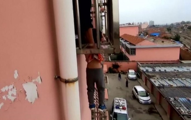 Bé trai bị mắc kẹt ngoài cửa sổ tầng 4. Ảnh cắt từ clip của CGTN