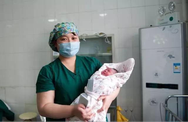 Bé được cuộn trong khăn ấm và đưa ra ngoài để tiêm hòng cùng với giấy tờ ghi thông tin cá nhân của bé.