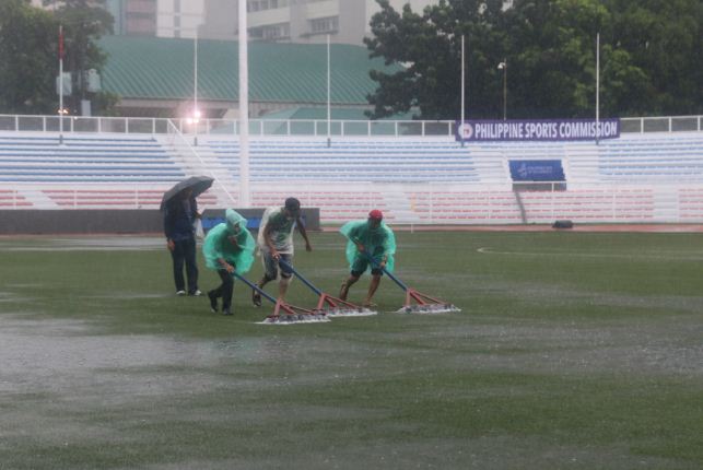 Nhân viên đang ra sức dọn nước đọng trên sân cỏ nhân tạo.