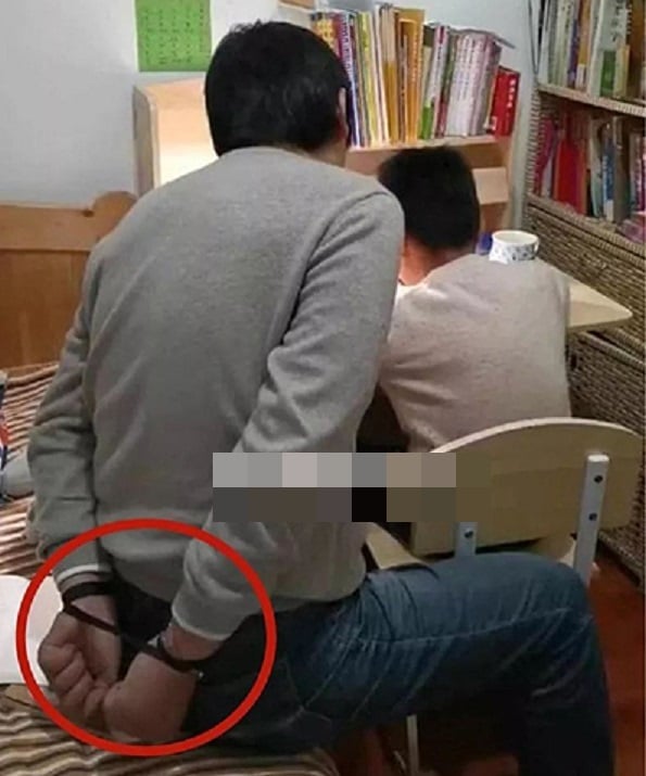 Người cha tự trói tay mình lại trong lúc dạy con học bài.  Ảnh: Sohu