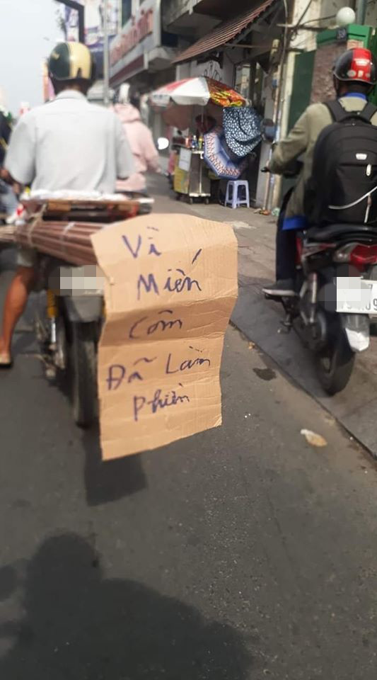 Hình ảnh người đàn ông chở vật liệu trên đường và tờ thông báo gây chú ý.