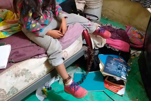 Bé gái bị xích chân vào giường.