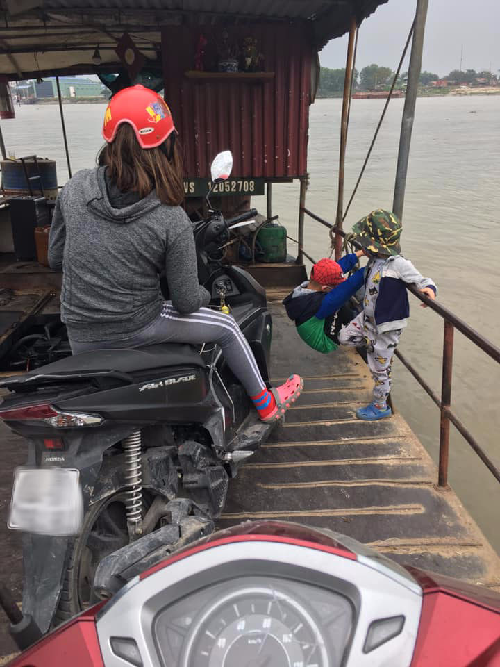 Hai đứa trẻ đu bám ở lan can phà và sự thờ ơ của người mẹ.