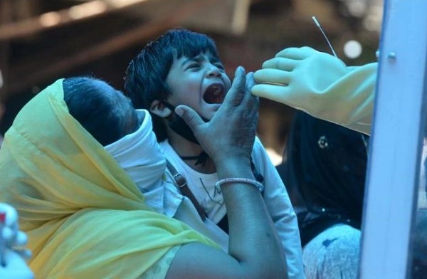  Một bé trai được nhân viên y tế lấy mẫu xét nghiệm Covid-19. (Ảnh: India Today)