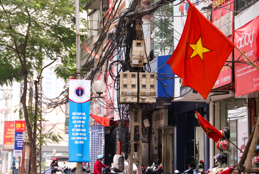 Xen kẽ với cờ hoa, biểu ngữ mừng ngày thống nhất đất nước là những băng rôn tuyên truyền về công tác phòng chống dịch. (Ảnh: ICTnews)