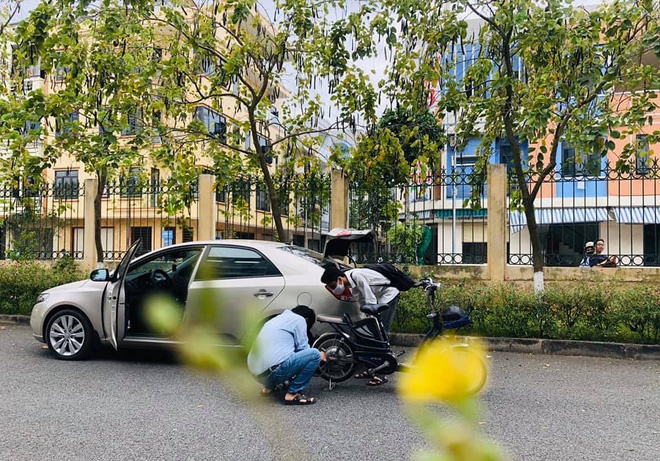 Thầy giáo dừng ô tô sửa xe cho học sinh giữa trưa nắng.