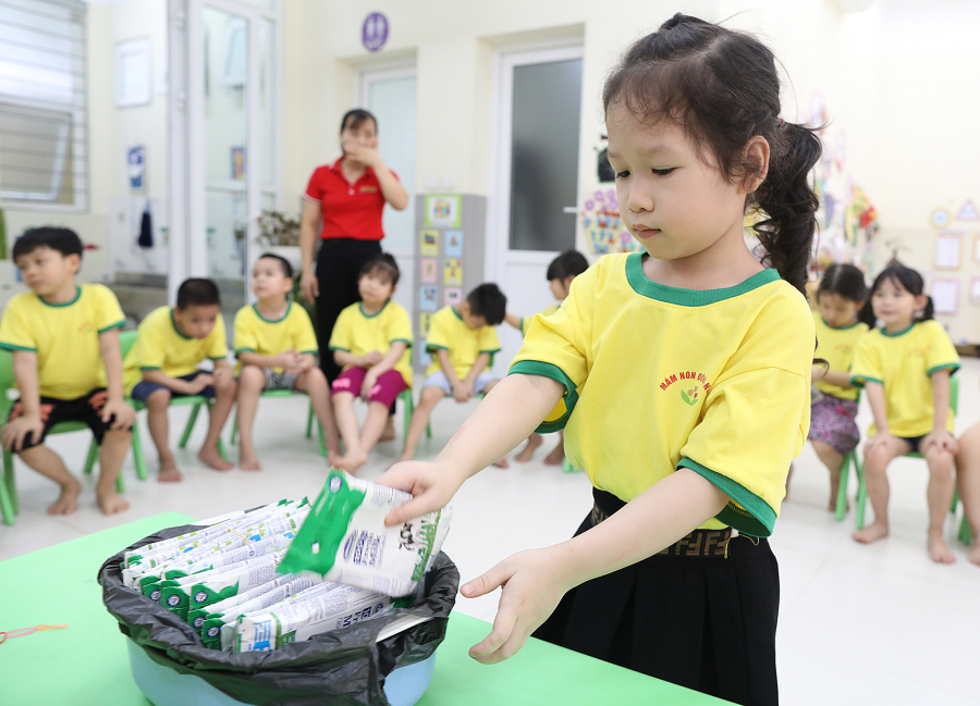 Các em học sinh được hướng dẫn cách gấp gọn và thu dọn hộp sữa sau khi sử dụng xong