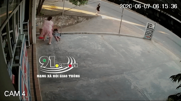 Người phụ nữ cầm chổi để gạt tay em bé ra khỏi đường dây diện.