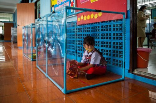 Các học sinh tiểu học được ngồi trong các hộp nhựa lắp giữa sàn nhà