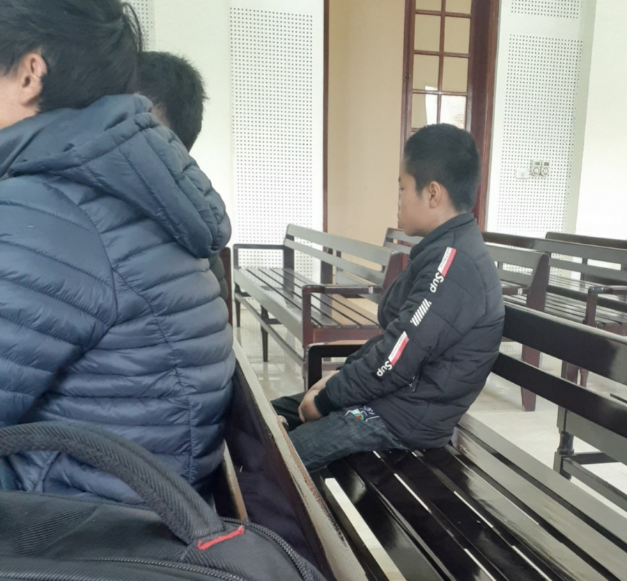 Cậu con trai út lặng lẽ ngồi nhìn mẹ đứng trước vành móng ngựa (Ảnh: Người đưa tin Pháp luật)