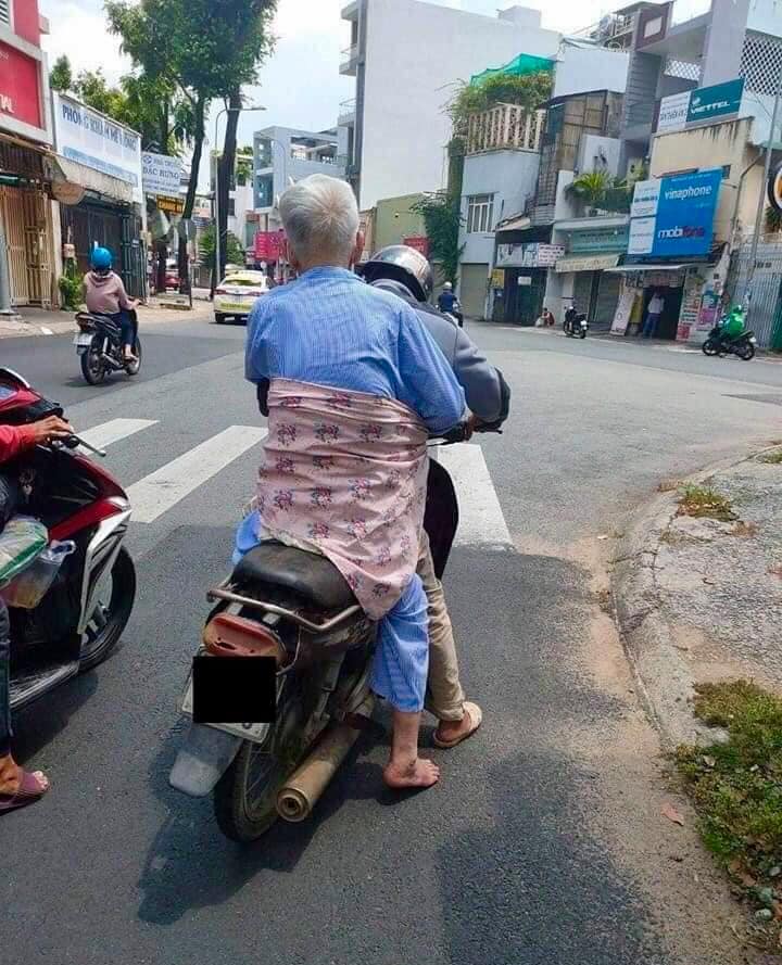 Người phụ nữ tốt bụng đã nhường tấm áo che nắng để quấn ông cụ vào người con trai, tránh bị ngã