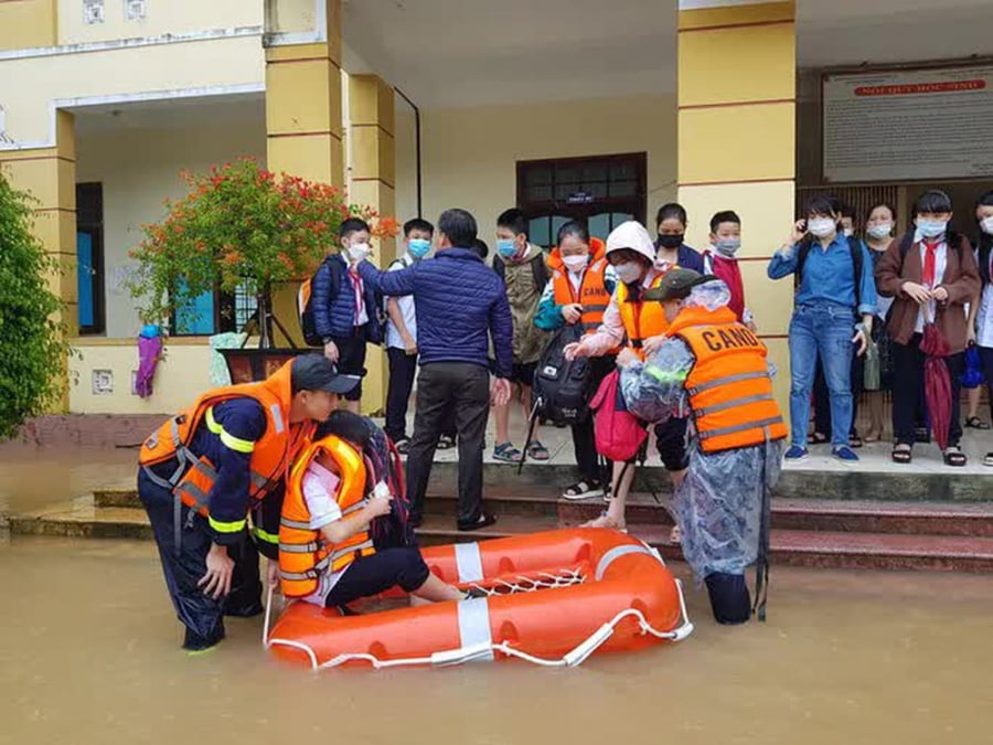 Lực lượng chức năng dùng xuồng để đưa học sinh ra ngoài. Ảnh: Người lao động.