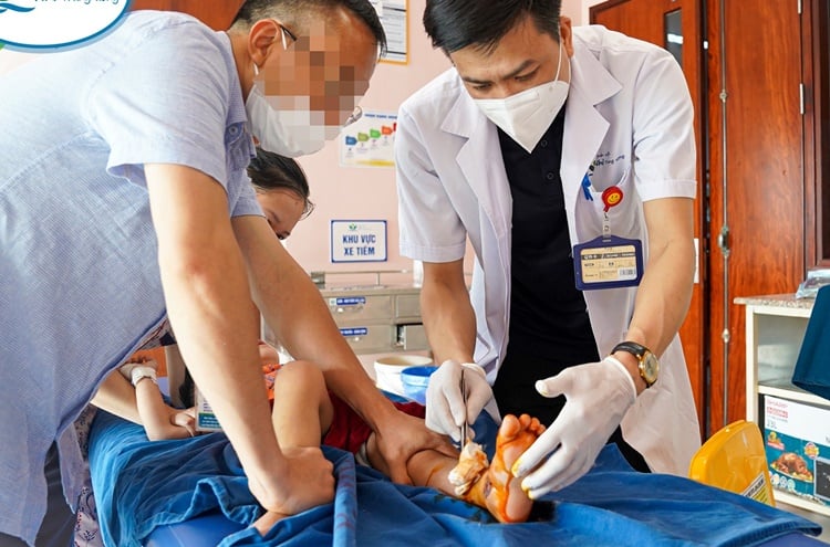 Bé D.P đang được bác sĩ xử lý vết thương (Ảnh: BV Nhi Trung ương).