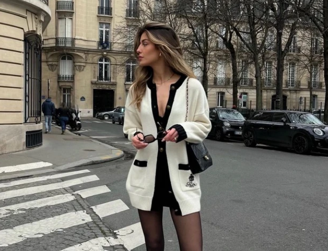 Kết hợp áo cardigan dáng dài với quần shorts ngắn hack dáng vô cùng. Khéo léo chọn kẻ viền, cô hoàn thiện set đồ bằng một chiếc quần tất lưới xuyên thấu, đôi bốt mũi vuông dáng dài và túi xách dây xích. Trên nền cardigan trắng, gam màu nào cũng có thể trở nên bắt mắt hơn