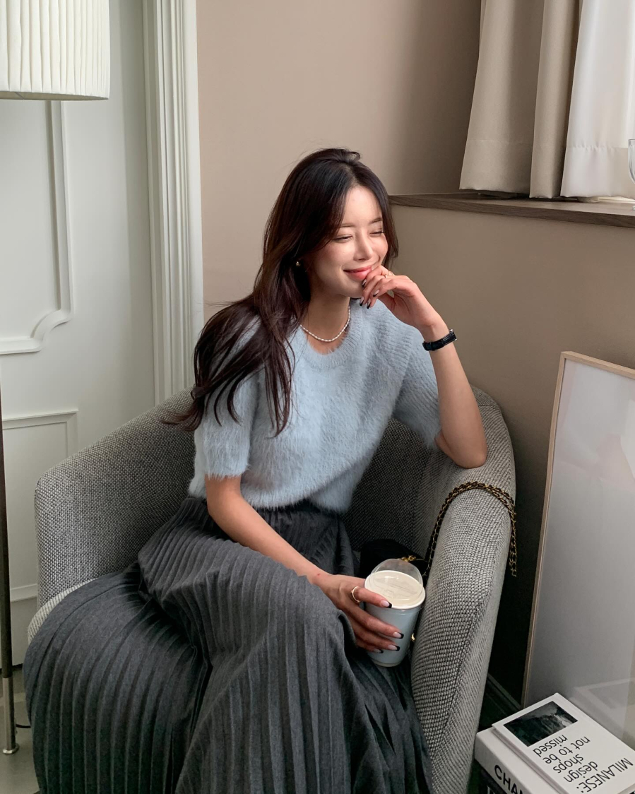 Áo len màu xanh pastel và chân váy màu ghi xám thêm phần sang chảnh nhờ chiếc vòng cổ ngọc trai. Sơ vin gọn gàng là 