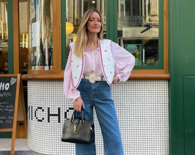 Một chiếc quần denim ống vẩy cùng ghi lê in hoa nhí xinh xắn và áo sơ mi kẻ sọc màu hồng pastel sẽ là những món đồ  tinh tế, đi giày slingback đế bằng cao gót và xách chiếc túi da tiện lợi.