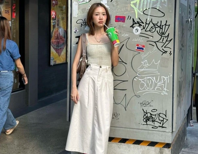 Cô nàng này phối áo hai dây trẻ trung cùng chân váy denim trắng. Nữ fashionista tạo điểm nhấn với tất cao cổ màu hồng đậm cùng túi xách da nâu.