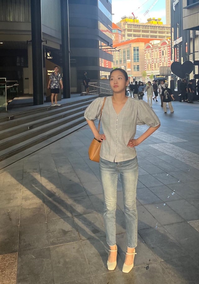 Cô chọn áo blouse tay bồng kết hợp với quần jeans ống đứng. Đôi giày cao gót mũi vuông, tông màu trắng rất phù hợp với outfit nữ tính.     