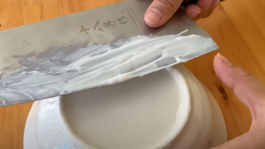 Đặt nghiêng lưỡi dao vào đế bát và kéo theo một chiều để mài cho lưỡi dao sắc bén trở lại.