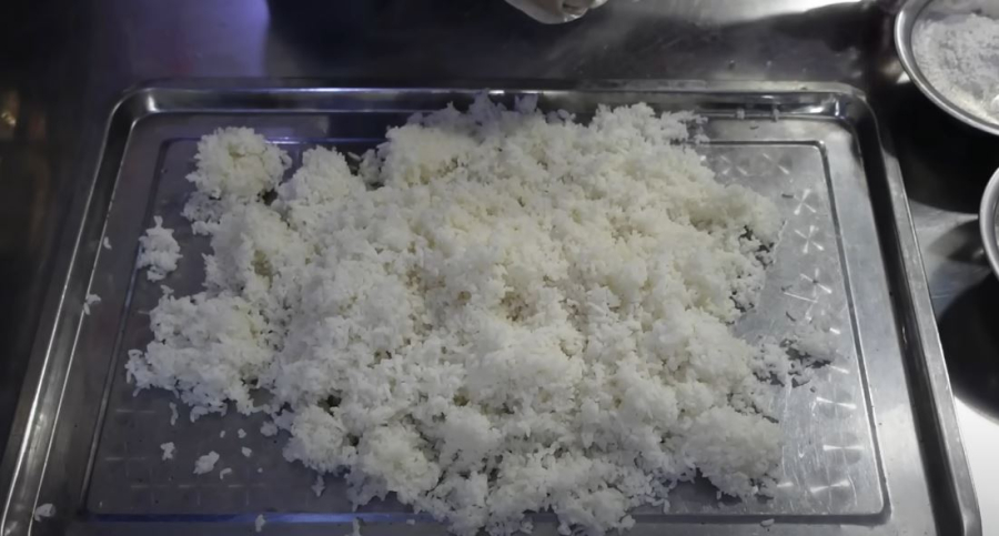 Rải đều cơm ra khay cho cơm nguội hoàn toàn. Có thể đem cơm đi phơi nắng hoặc hong trước quạt để bề mặt hạt cơm se lại.