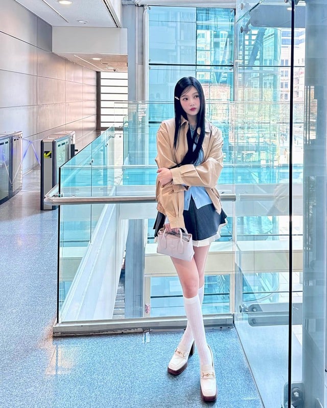 Áo khoác màu be phối cùng tất cao cổ và đôi loafer trắng sành điệu hút mắt.