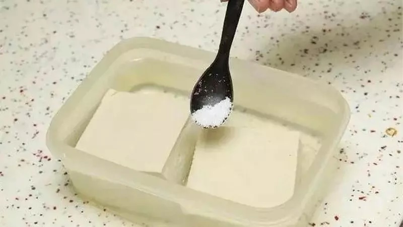 Hòa tan muối với nước nóng theo tỷ lệ 1 phần muối với 4 phần nước rồi ngâm đậu phụ trong đó trong khoảng 15 phút
