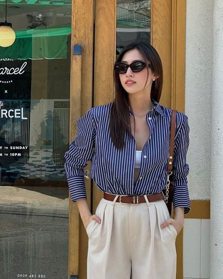 Áo sơ mi kẻ và quần xếp ly trắng, mix thêm phụ kiện để nâng tầm outfit. Mỹ nhân sinh năm 2000 nhấn nhá một chiếc thắt lưng bản to màu da bò, ton sur ton cùng túi xách tạo nên tổng thể thời thượng, lôi cuốn    