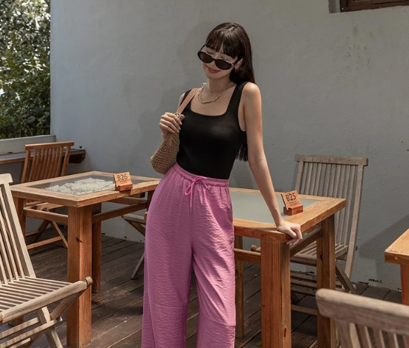 Tank top màu đen và quần ống suông tông màu hồng nổi bần bật, nàng nên sơ vin để tôn dáng hiệu quả hơn. Những món đồ như túi cói, dép lê đảm bảo điểm nhấn thú vị. 