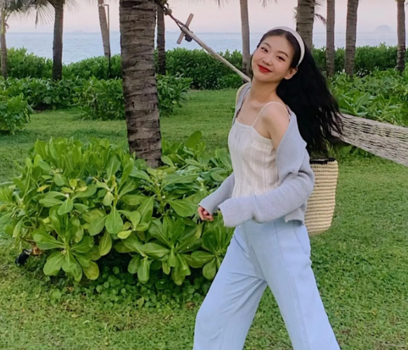 Công thức gồm áo hai dây trắng kết hợp với quần jeans xanh, diện mạoc trở nên ngọt ngào hơn nhờ bờm tóc và chiếc túi cói.    