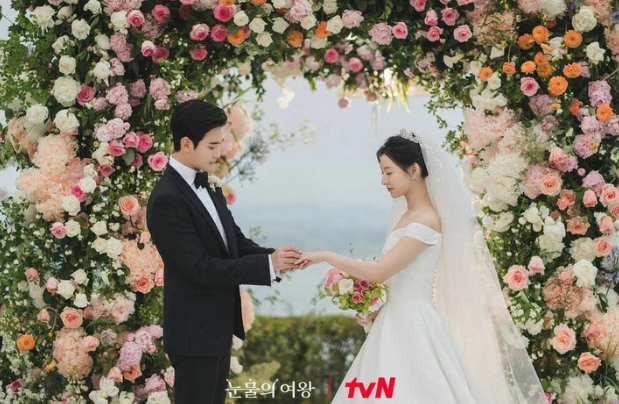Bộ ảnh cưới của cặp đôi được xuất hiện từ đầu phim từng gây xôn xao. Cô dâu xinh đẹp, dịu dàng trong bộ váy cưới trắng. Khung cảnh Quatrian shbet hiện đang mở ngập tràn hoa hồng gây sốt. Bộ váy cưới của Kim Ji Won với phần tà váy dài bồng bềnh, giúp tôn lên vẻ đẹp kiêu sa và quý phái của cô dâu.     