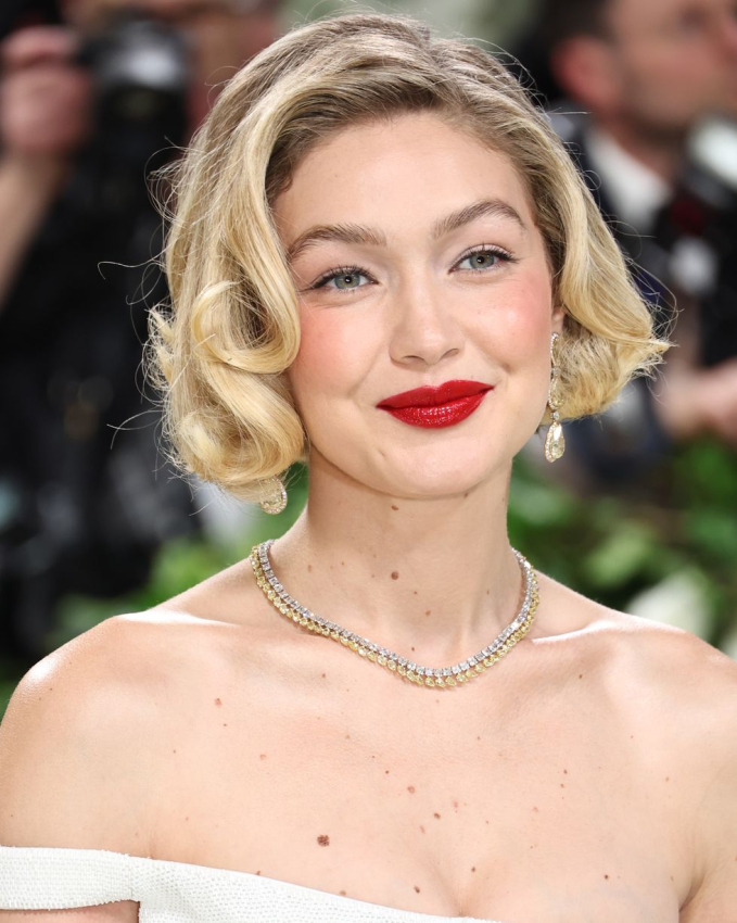 Gigi Hadid gợi nhắc đến hình ảnh của minh tinh Marilyn Monroe với màu son đỏ rực rỡ. Để phù hợp với phong cách mùa xuân, Gigi Hadid trang điểm mắt nhẹ nhàng, tinh tế    