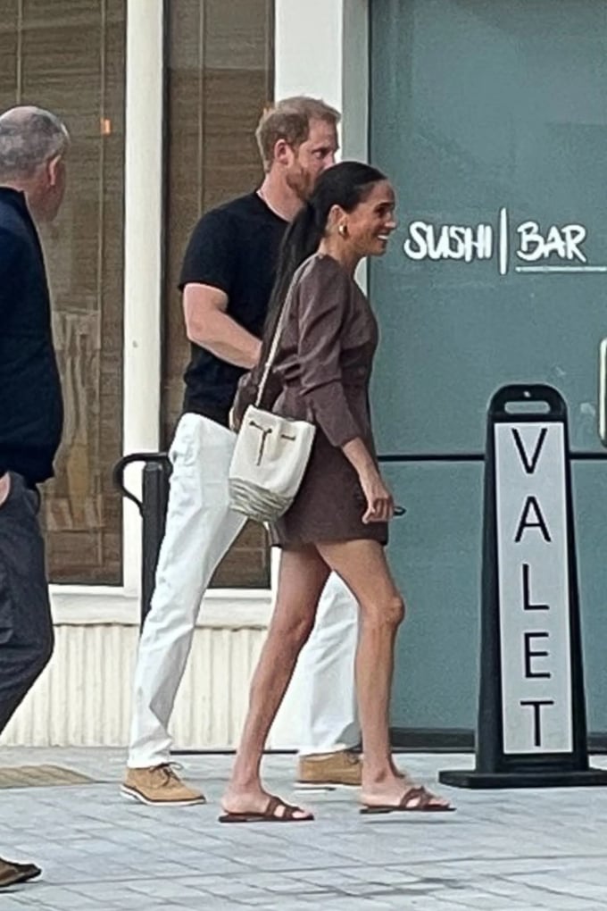 Meghan Markle đeo túi xách màu trắng, đi sandal tông màu nâu.