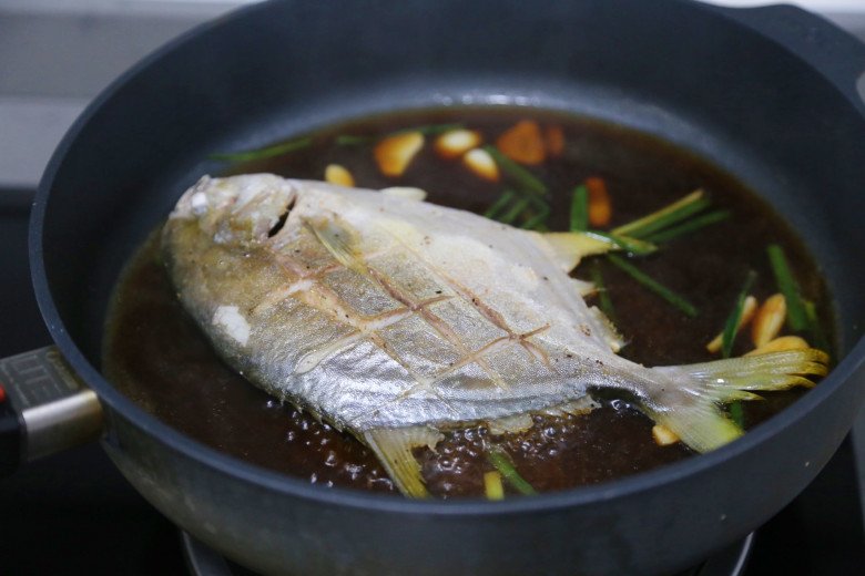 Sau khi rán cá chim vàng đều hai mặt thì cho vào chảo sốt với nước tương.